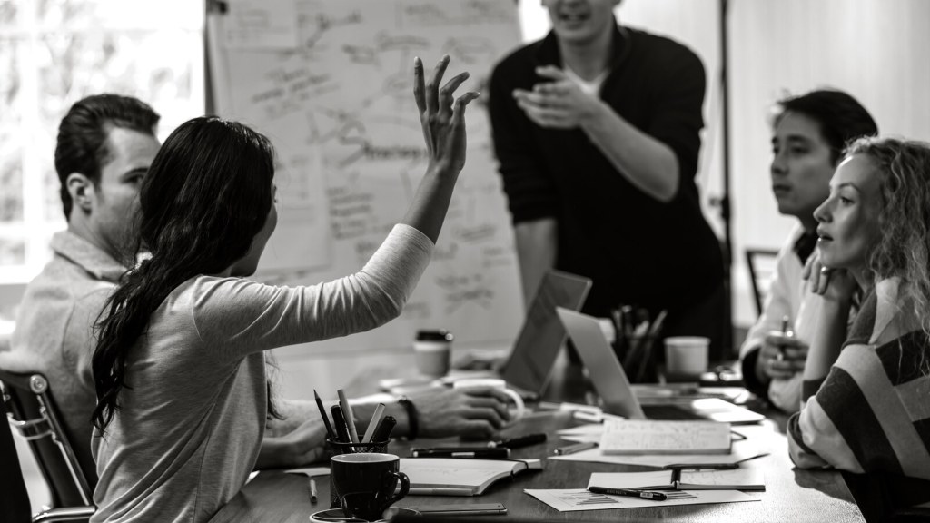 One hand raised in a meeting